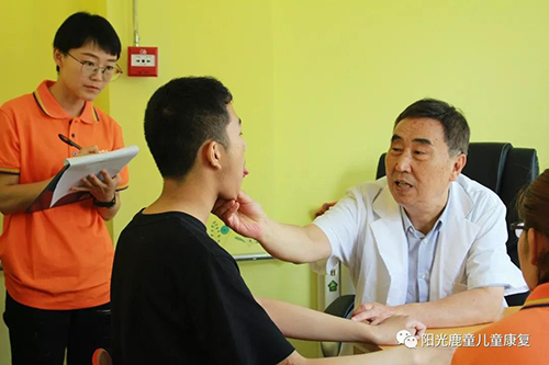 李光玉主任为孩子做检查，康复老师在旁记录